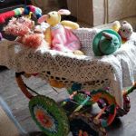 Toys relaxing in the yarn-bombed pram, Wild about Wool 2019, Poltimore House